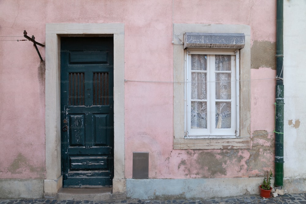Un edificio rosa con una puerta y ventana negras