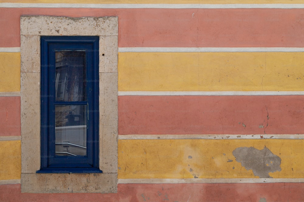 una ventana azul en una pared amarilla y rosa