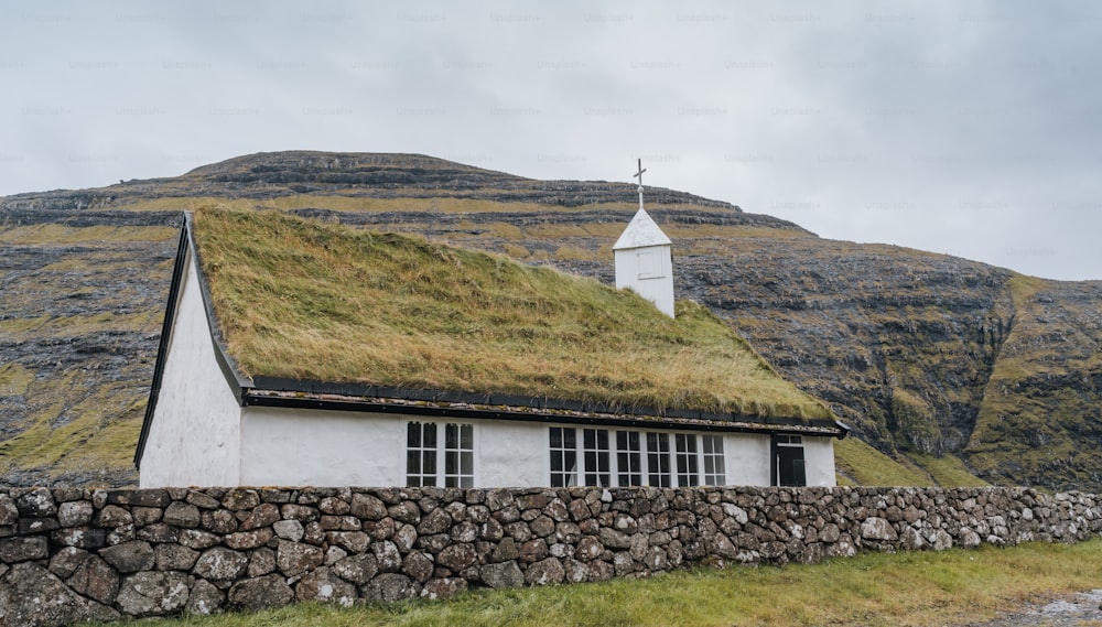 une maison avec un toit en herbe et un mur de pierre