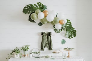 Una mesa blanca cubierta con muchos globos verdes y blancos
