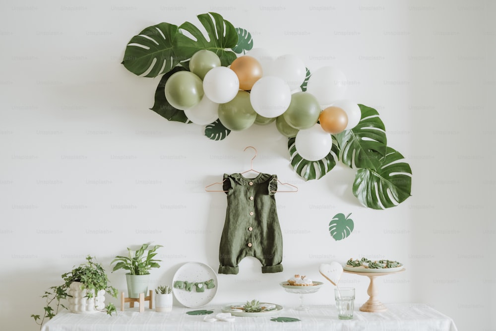 a white table topped with lots of green and white balloons