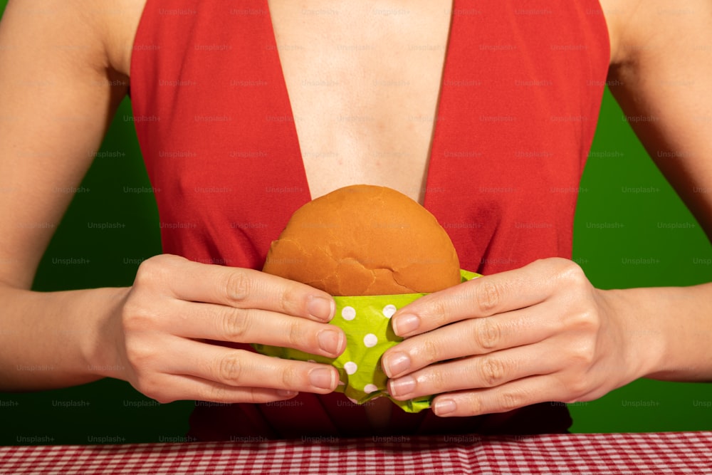 a woman in a red top holding a sandwich in her hands