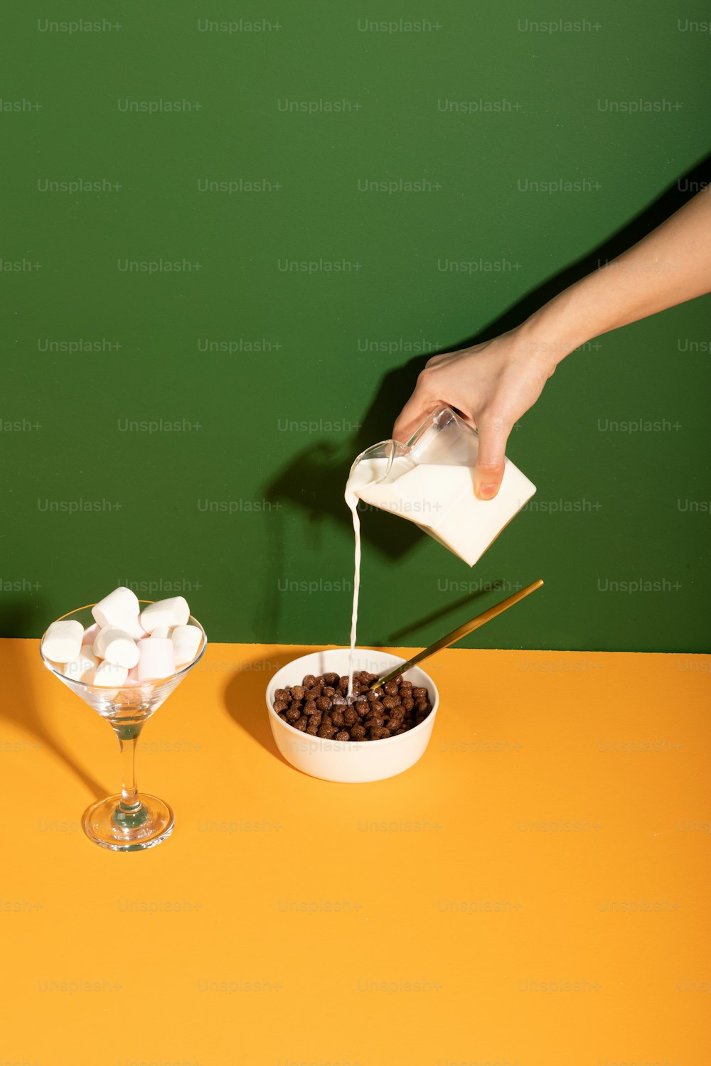a person pouring milk over a bowl of marshmallows