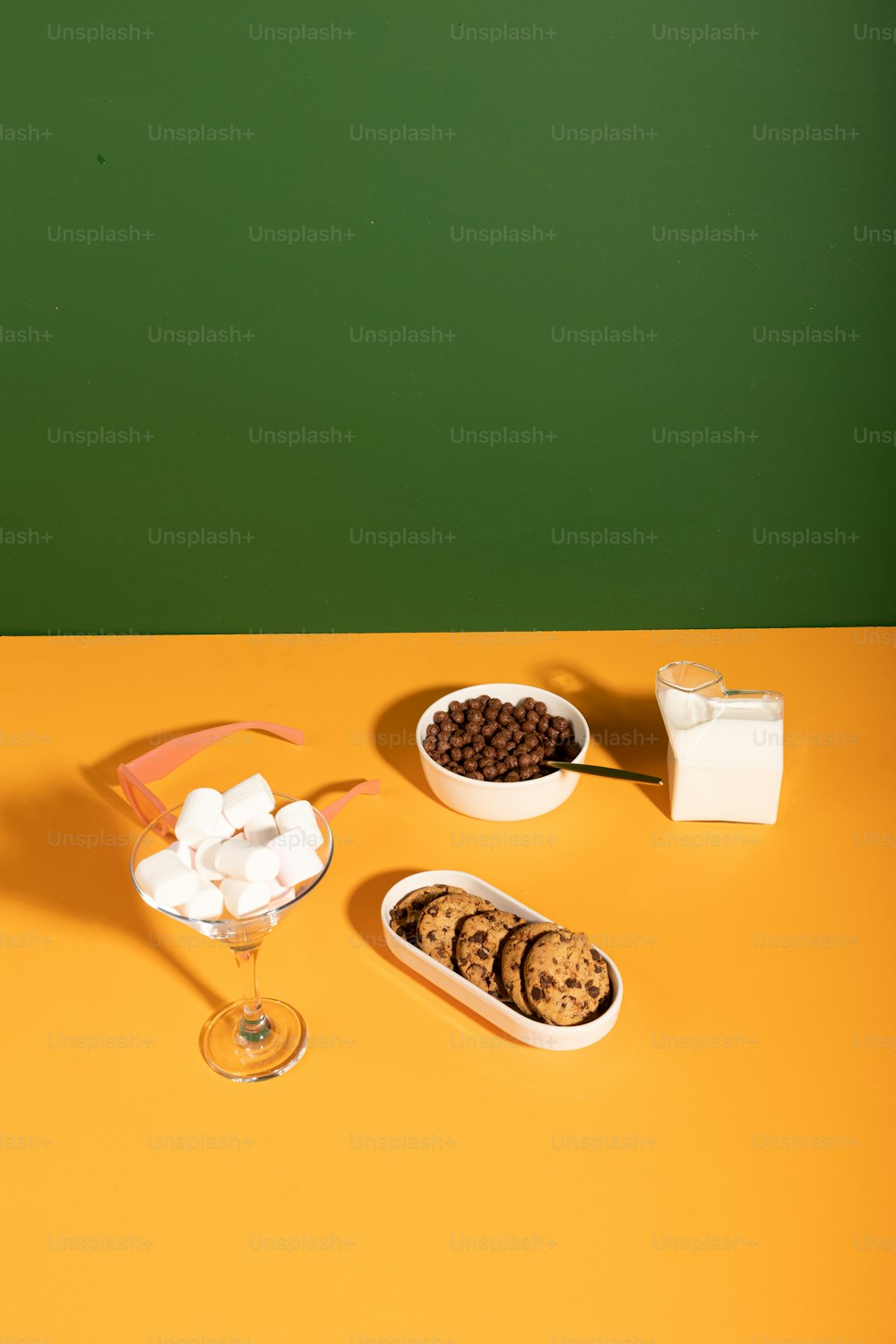 a yellow table topped with bowls of food and a glass of wine