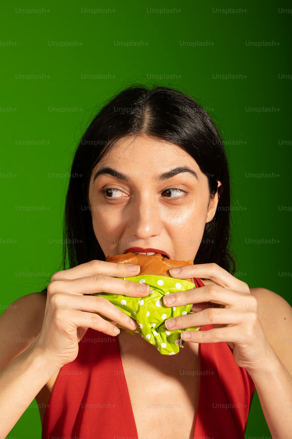 a woman in a red dress eating a sandwich