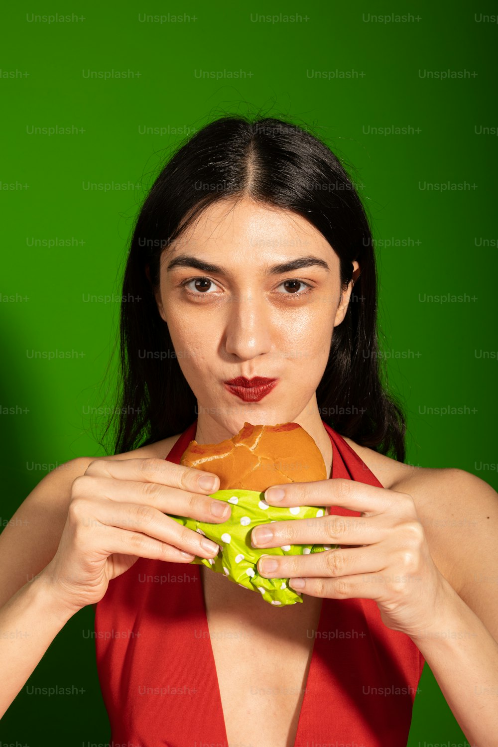 a woman in a red dress holding a sandwich