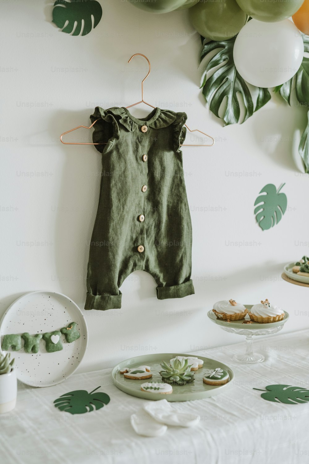 a baby's green romper hanging on a wall