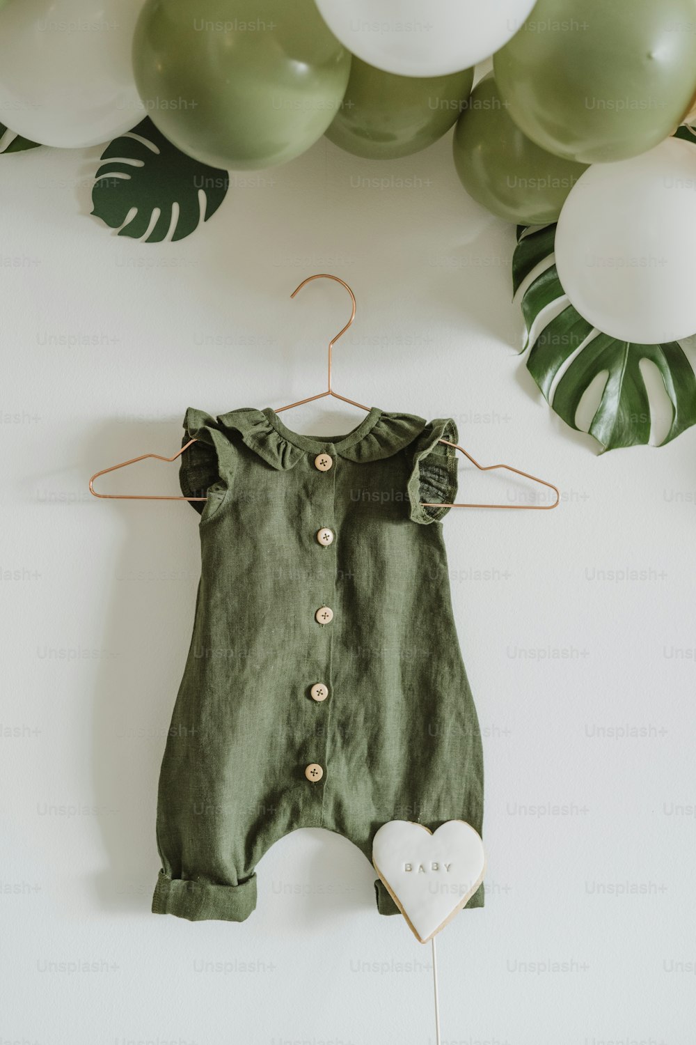 a green romper with a heart hanging from it