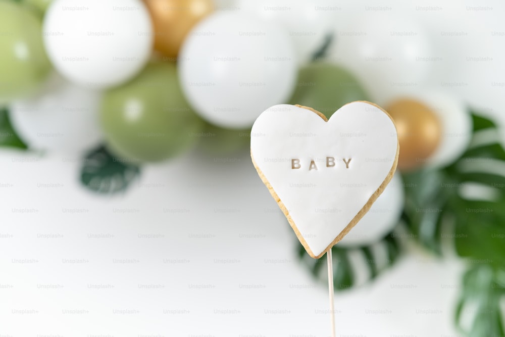 Un pastel en forma de corazón en un palo con la palabra bebé escrita en él