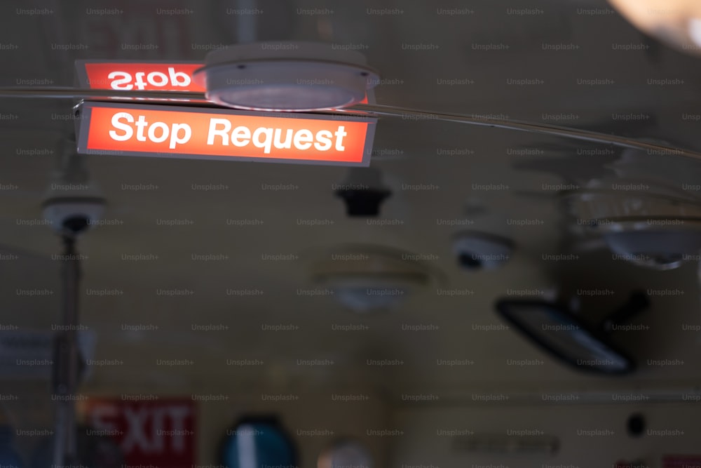 un panneau rouge qui dit Stop demande suspendue à un plafond