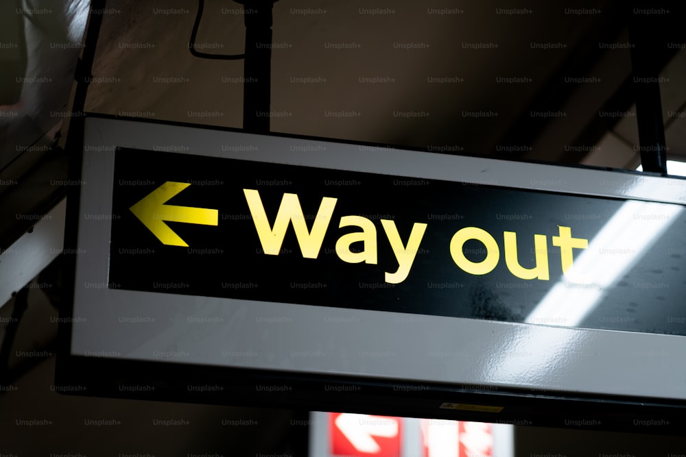 a sign that says way out hanging from a ceiling