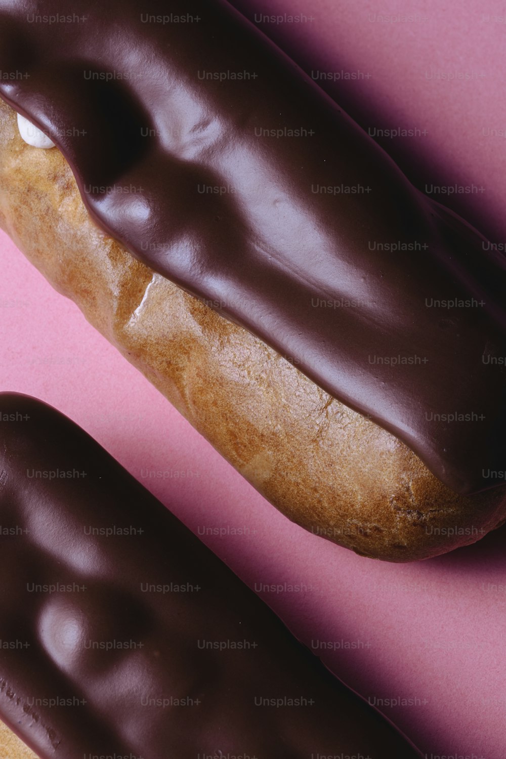 a donut with chocolate icing on a pink surface