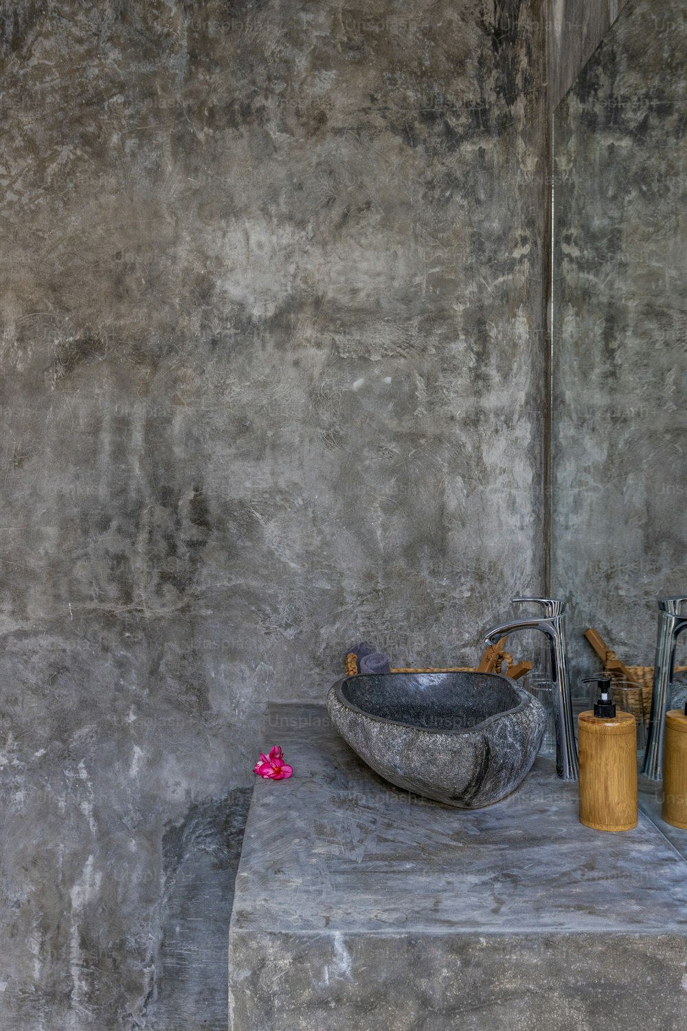 un baño con paredes de hormigón y un lavabo
