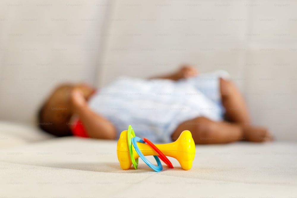 um bebê deitado em uma cama com um brinquedo