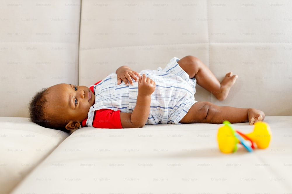 a baby laying on a couch playing with a toy