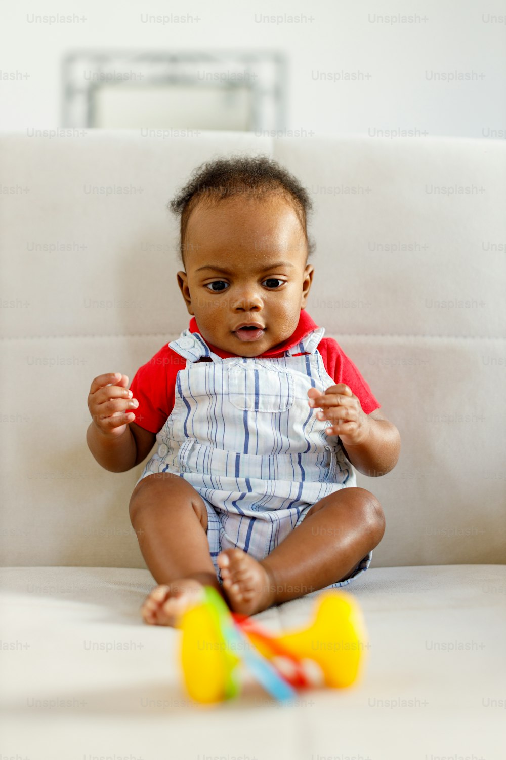 a baby sitting on a couch playing with a toy