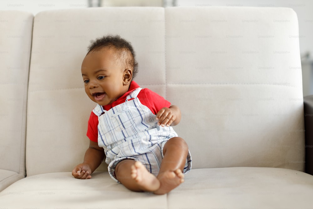 a baby sitting on a white couch smiling