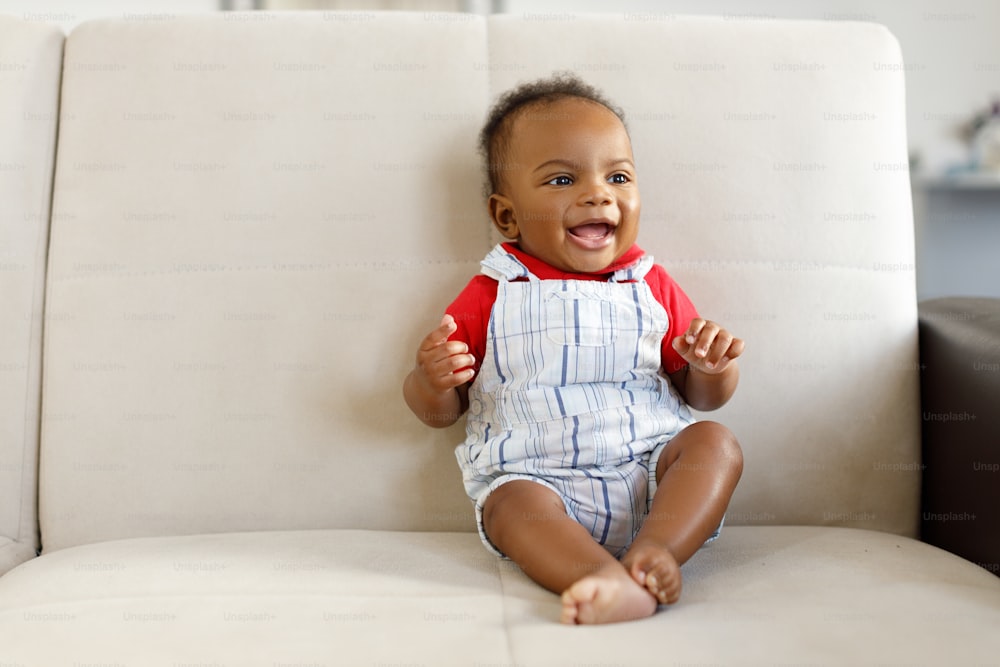 a baby sitting on a white couch smiling