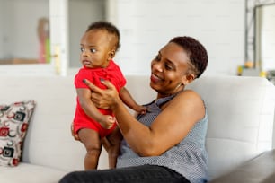 une femme assise sur un canapé tenant un bébé