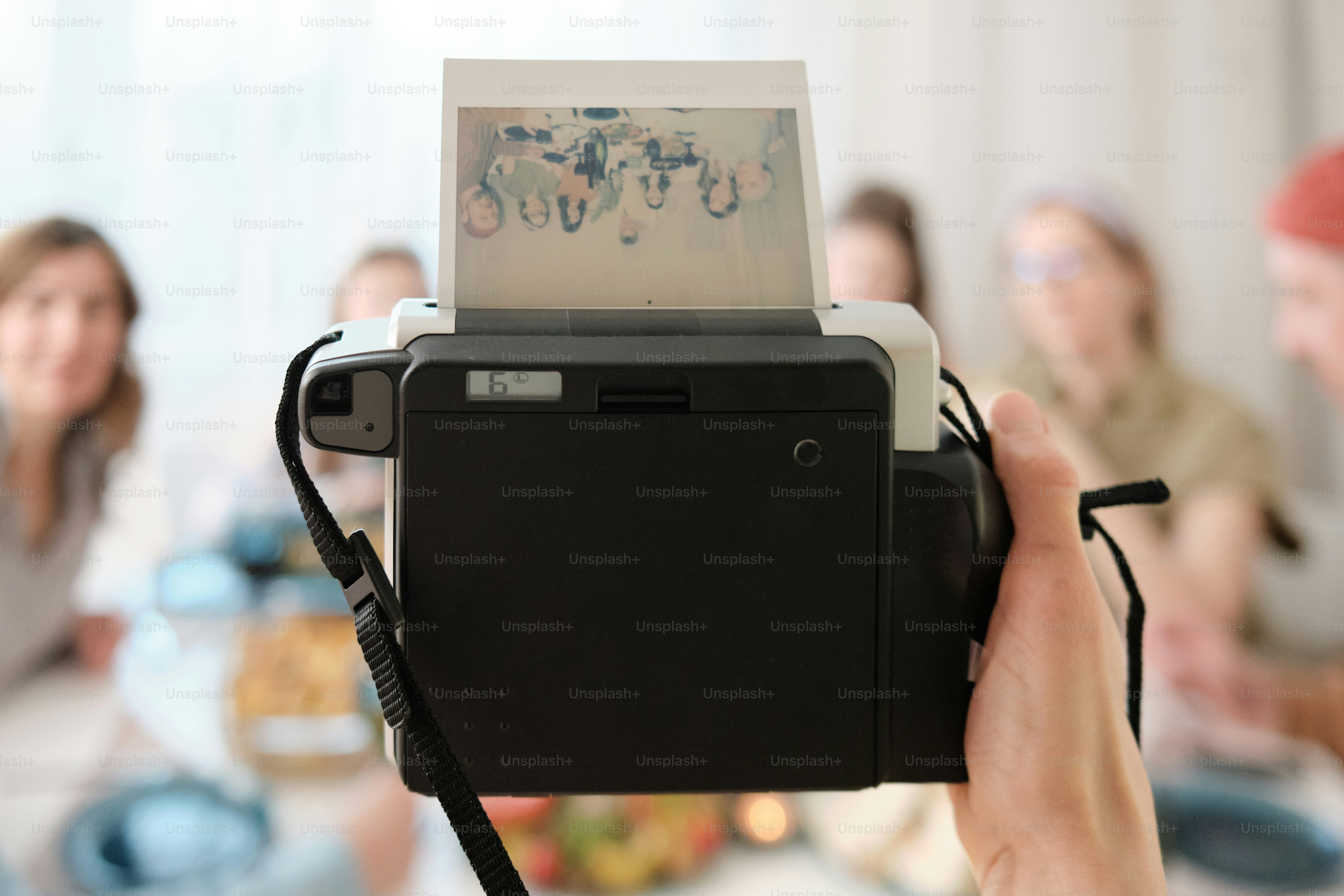 Group of friends at dinner taking pictures with instant print camera