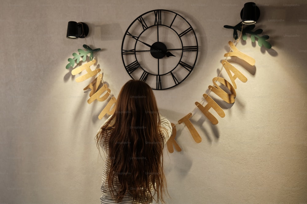 a woman standing in front of a wall clock