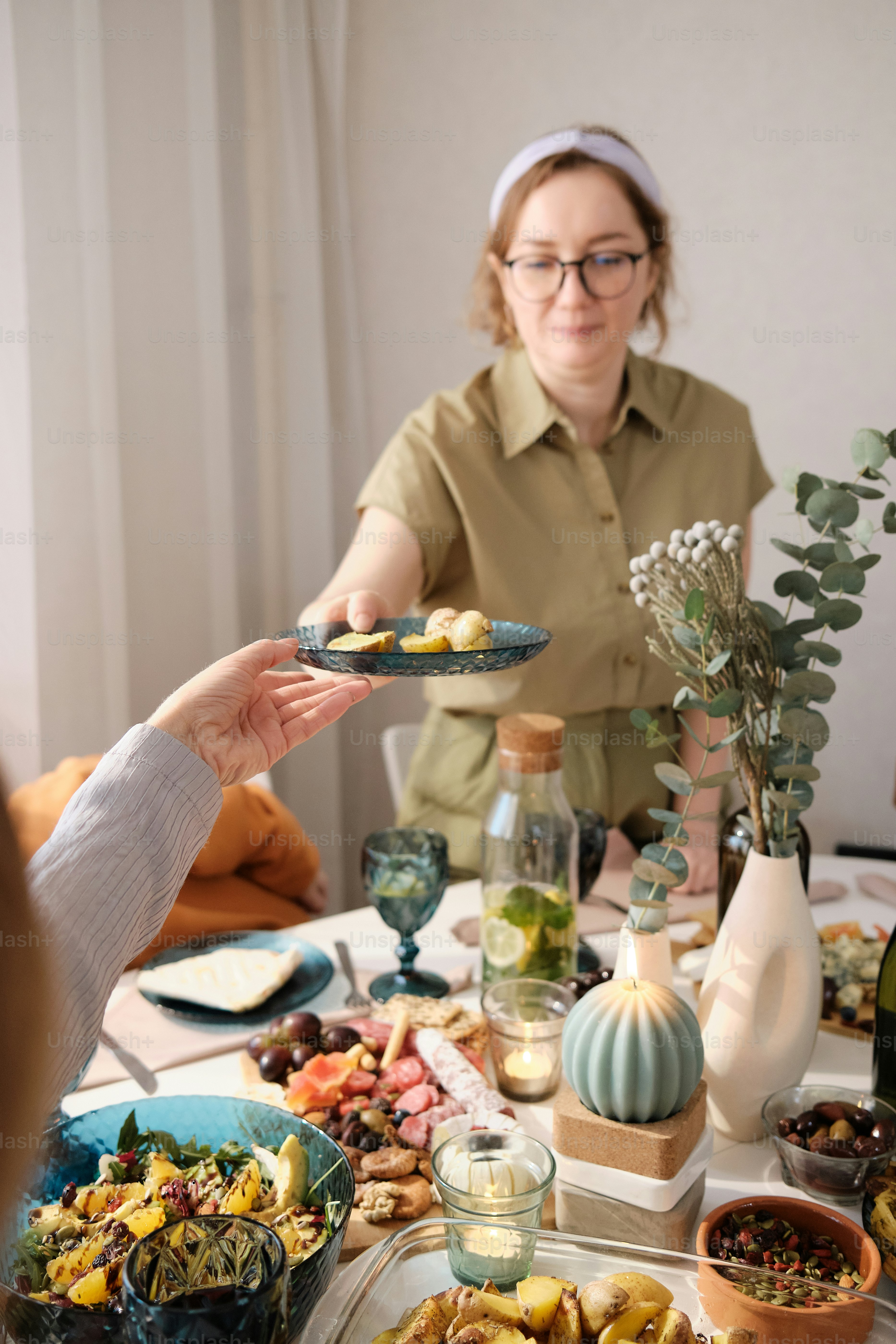 Eine Frau hält einen Teller mit Essen an einem Esstisch