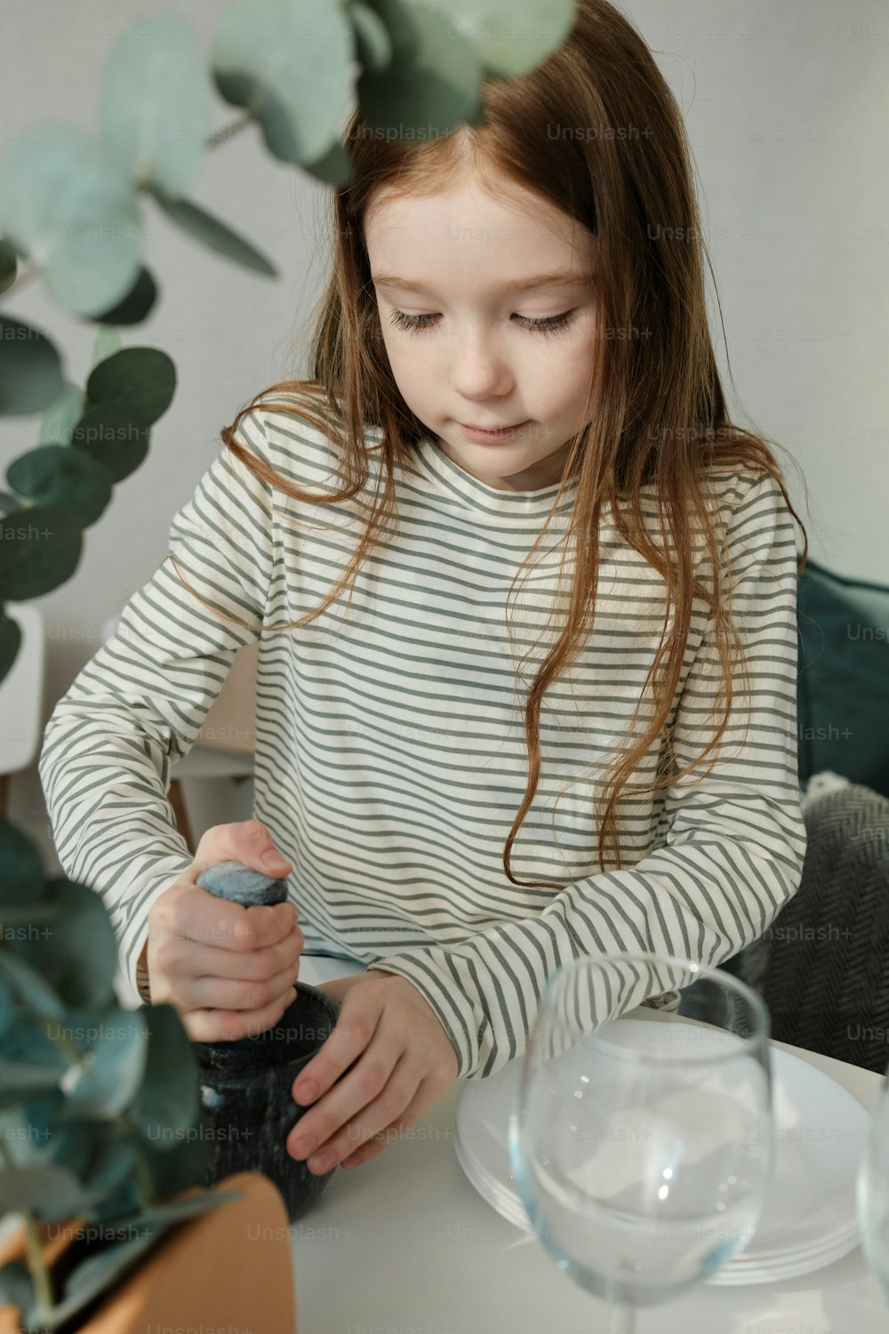 Ein kleines Mädchen sitzt an einem Tisch mit einer Flasche Wasser
