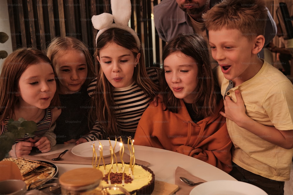 a group of children sitting around a table with a cake