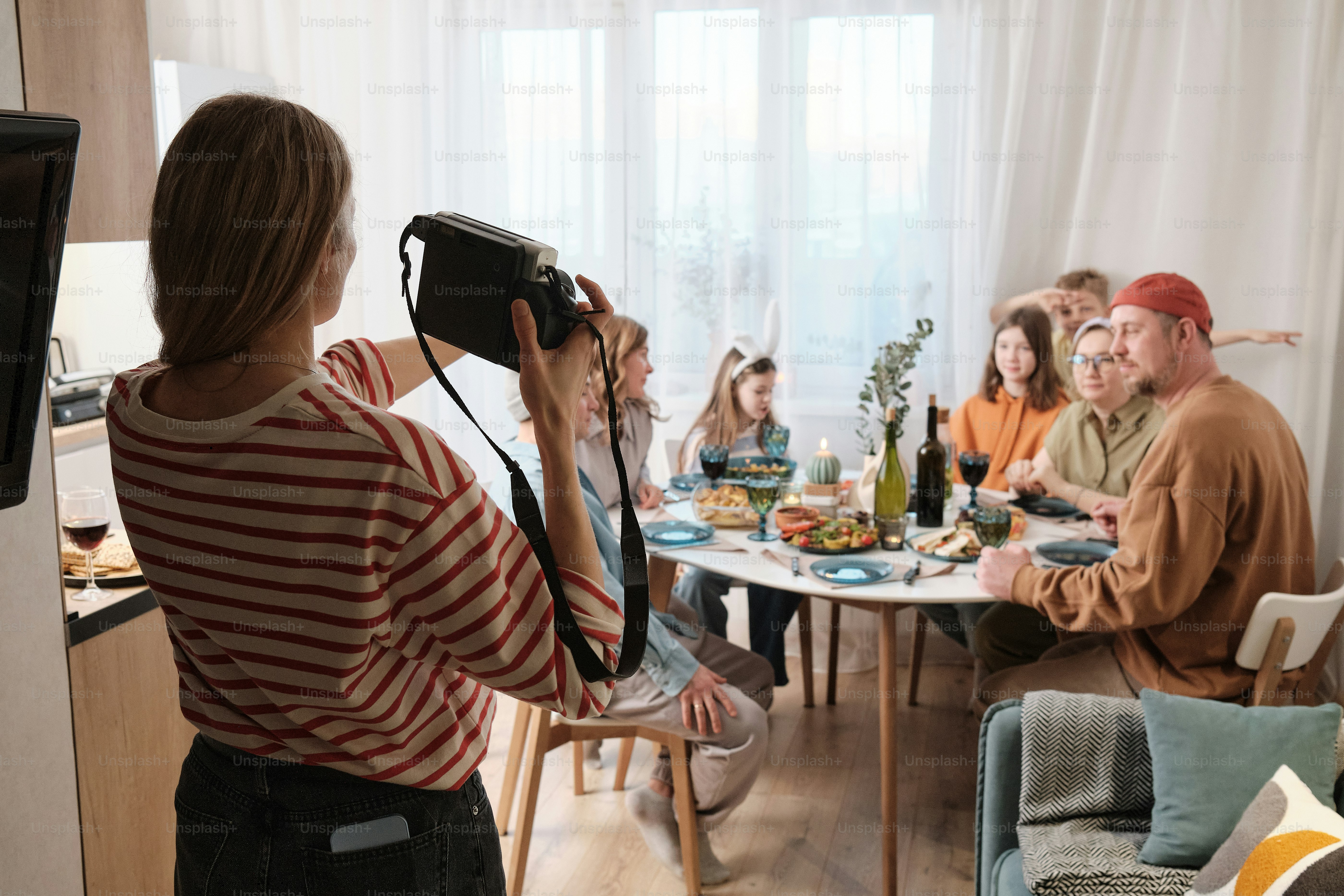 uma mulher tirando uma foto de um grupo de pessoas sentadas ao redor de uma mesa