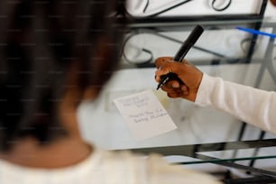 uma mulher segurando uma caneta e escrevendo em um pedaço de papel