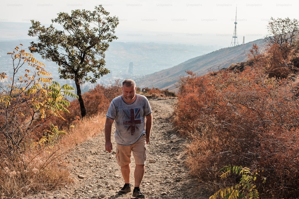 a man walking down a dirt path in the mountains