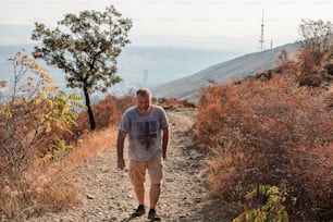 a man walking down a dirt path in the mountains