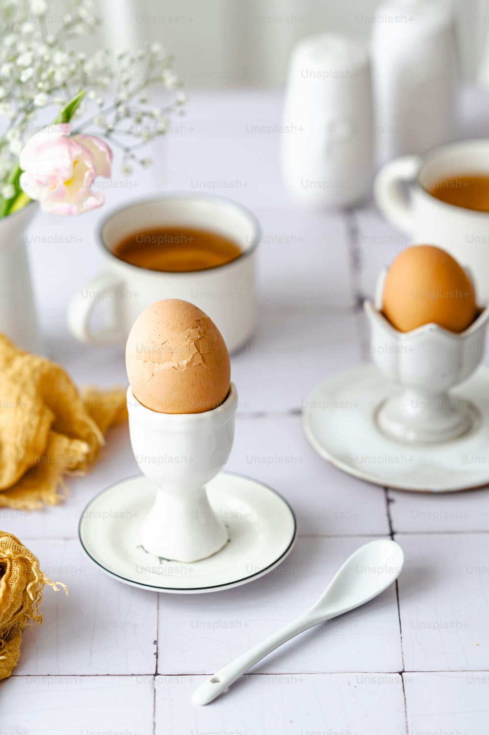 a table topped with two eggs and cups of coffee
