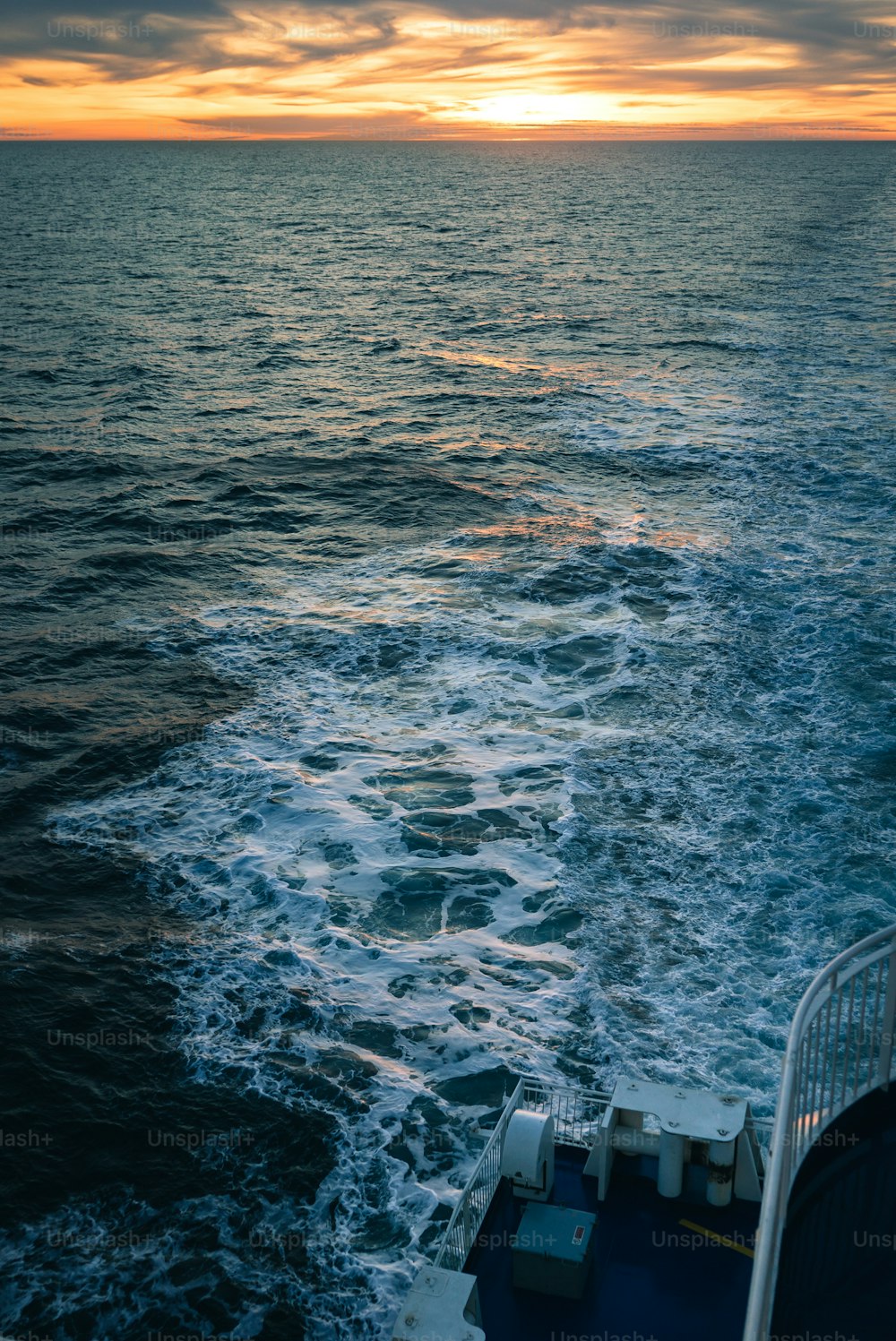 the sun is setting over the ocean as seen from a boat