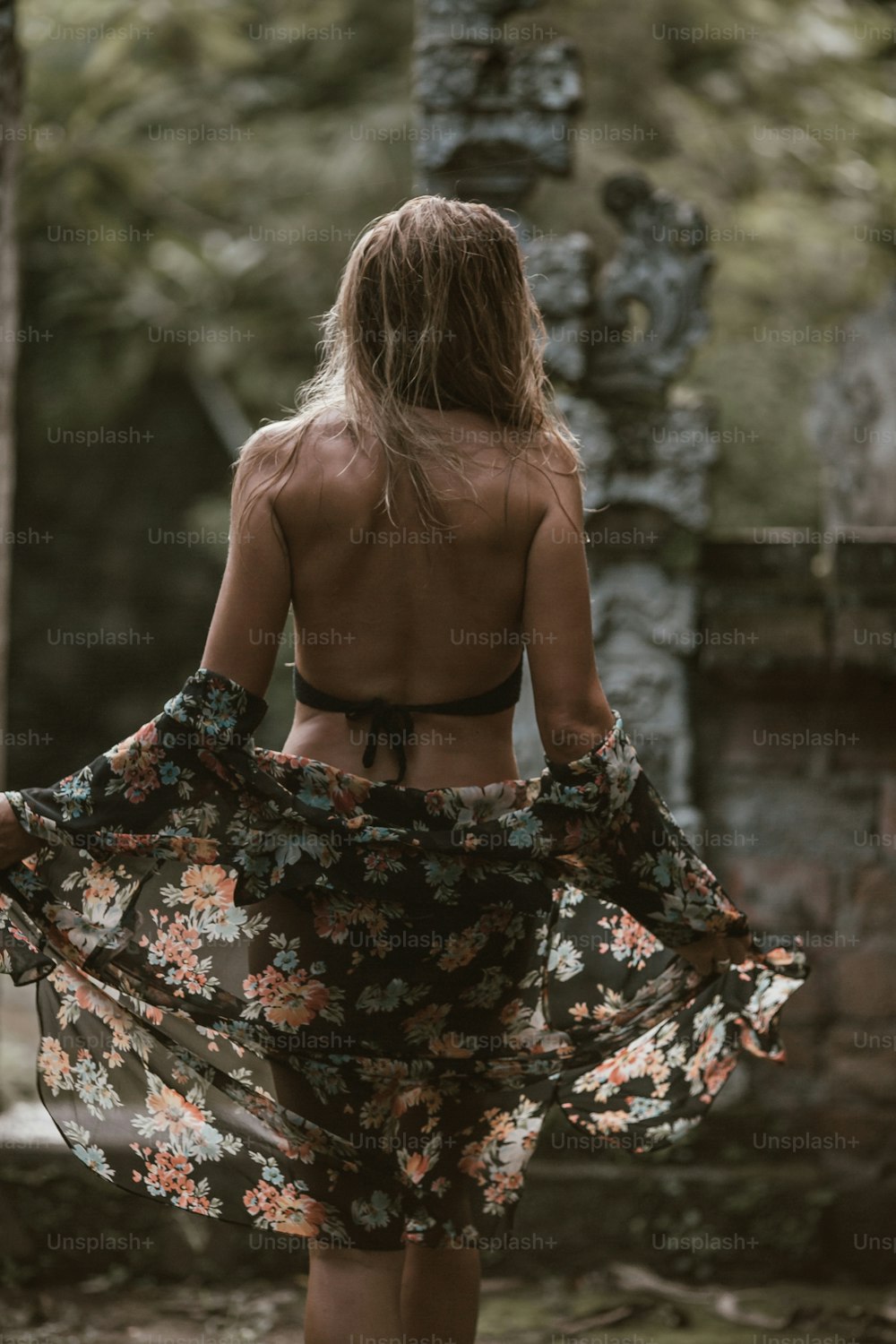 a woman in a floral dress walking through a forest