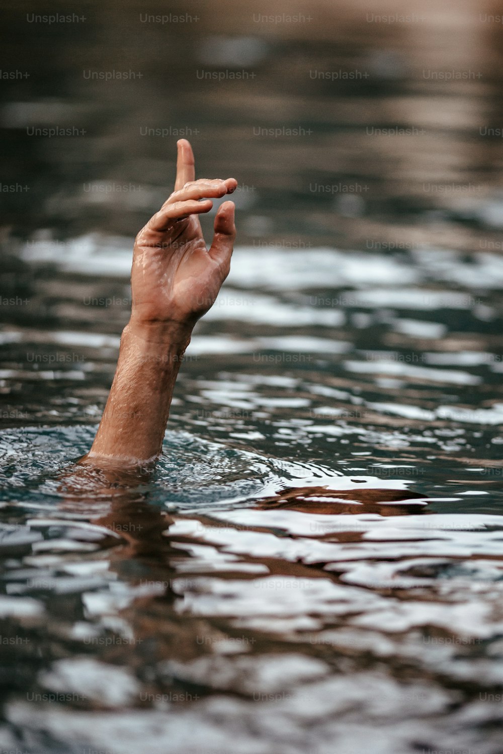 uma mão na água fazendo um sinal de paz