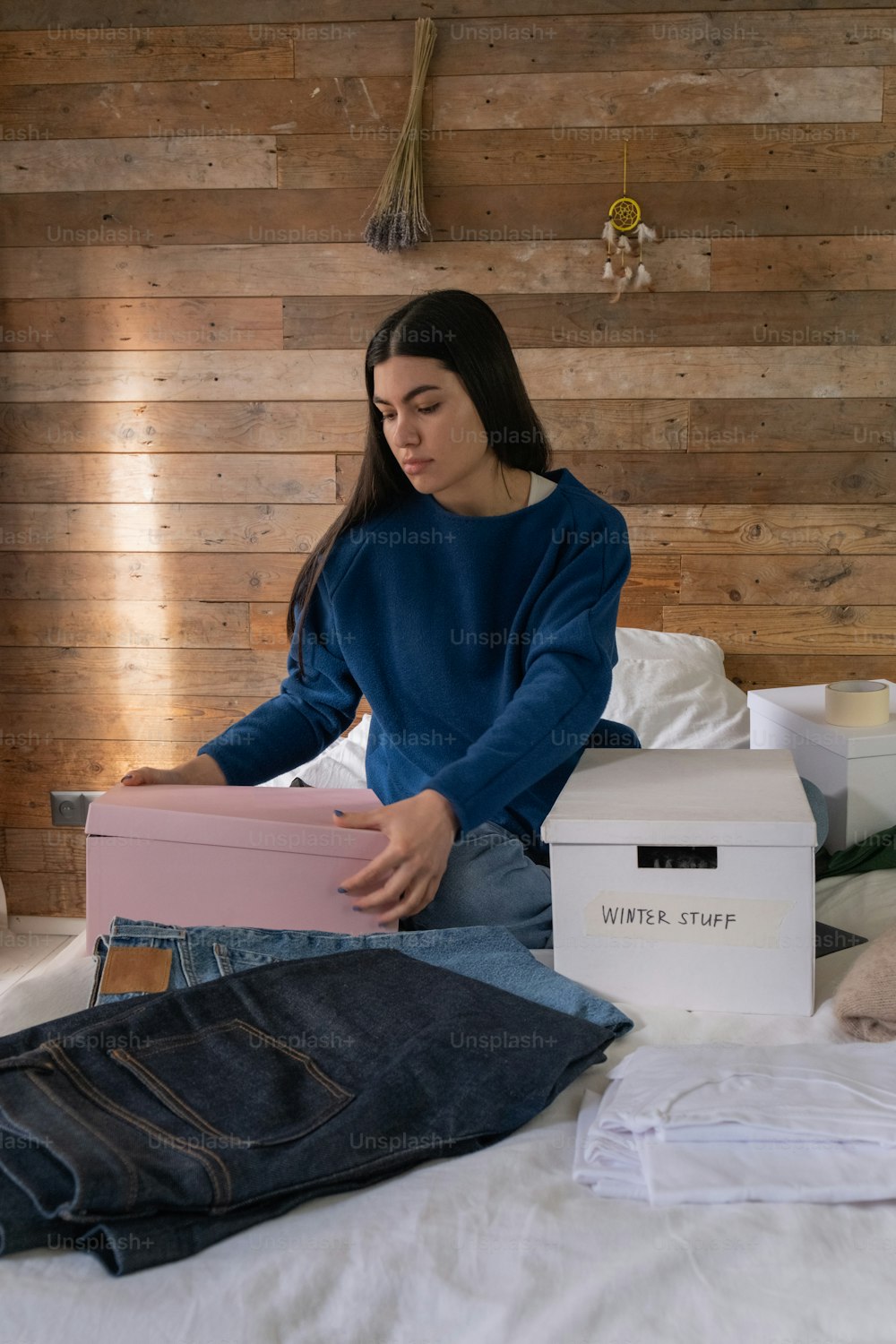 a woman sitting on a bed holding a box