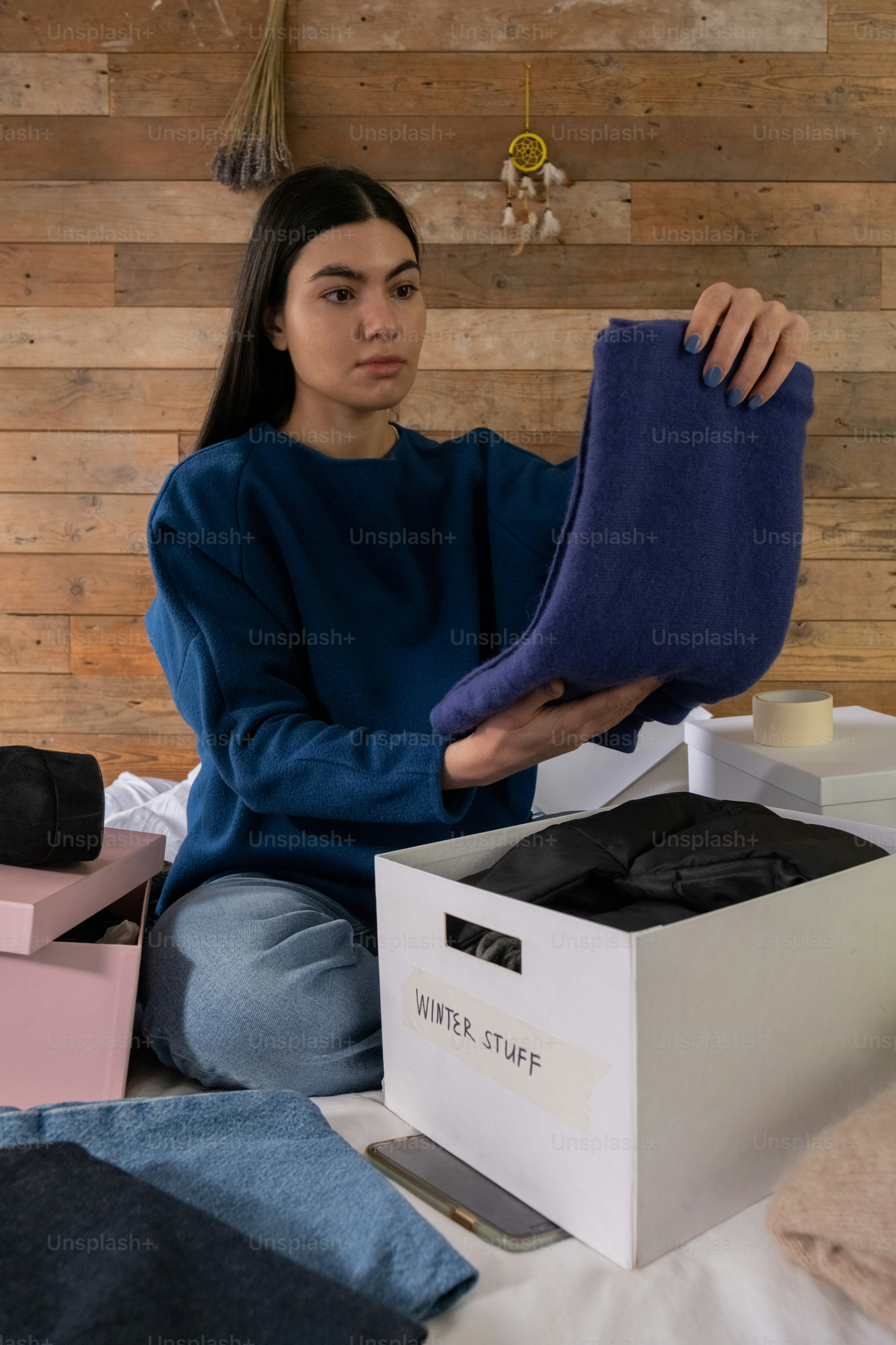 uma mulher sentada em uma cama segurando um material roxo