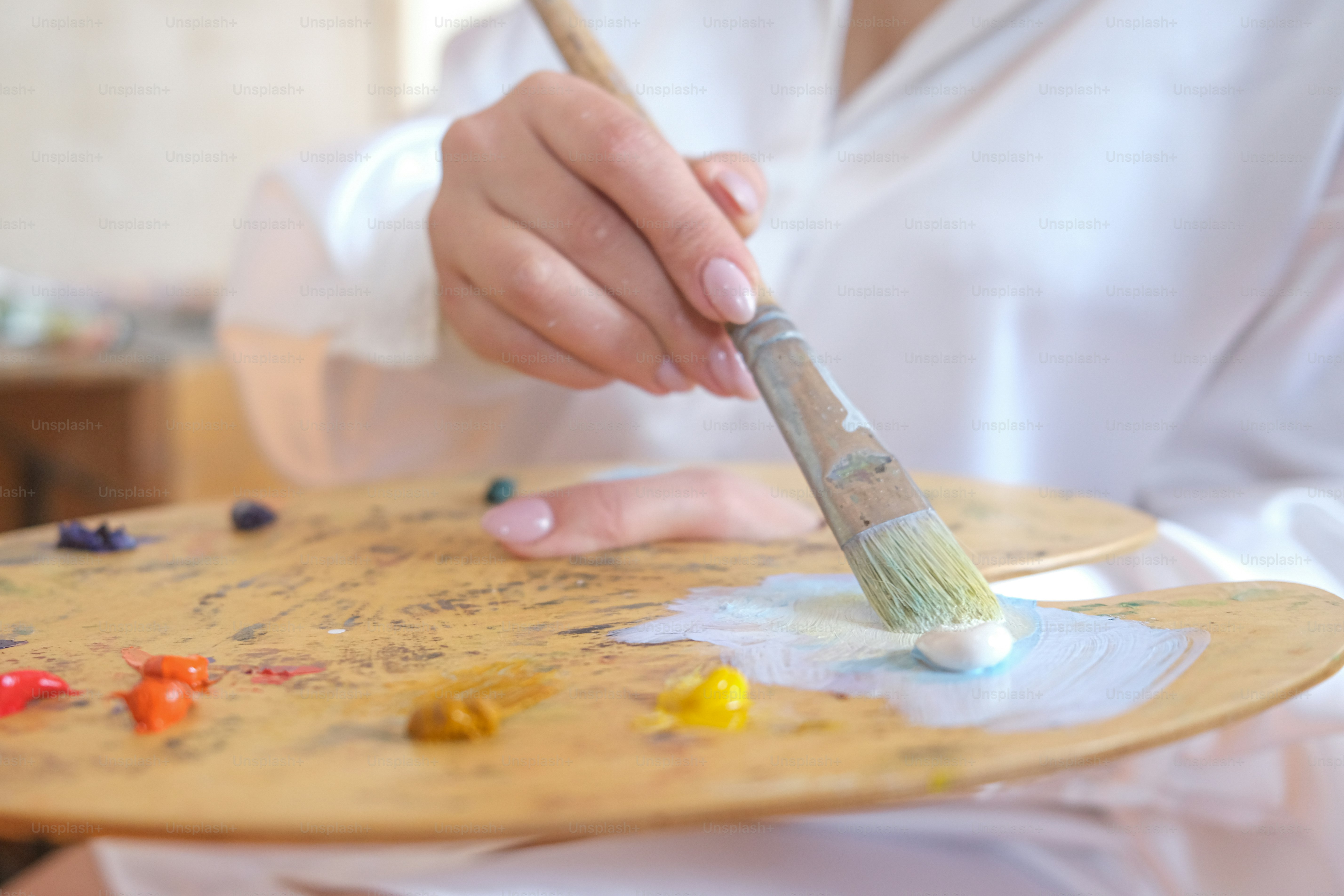 a person holding a paintbrush on a wooden tray