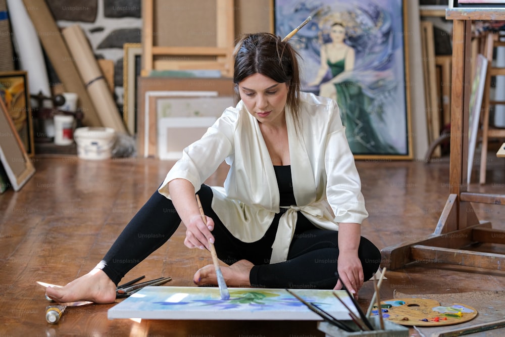 Eine Frau sitzt auf dem Boden und malt