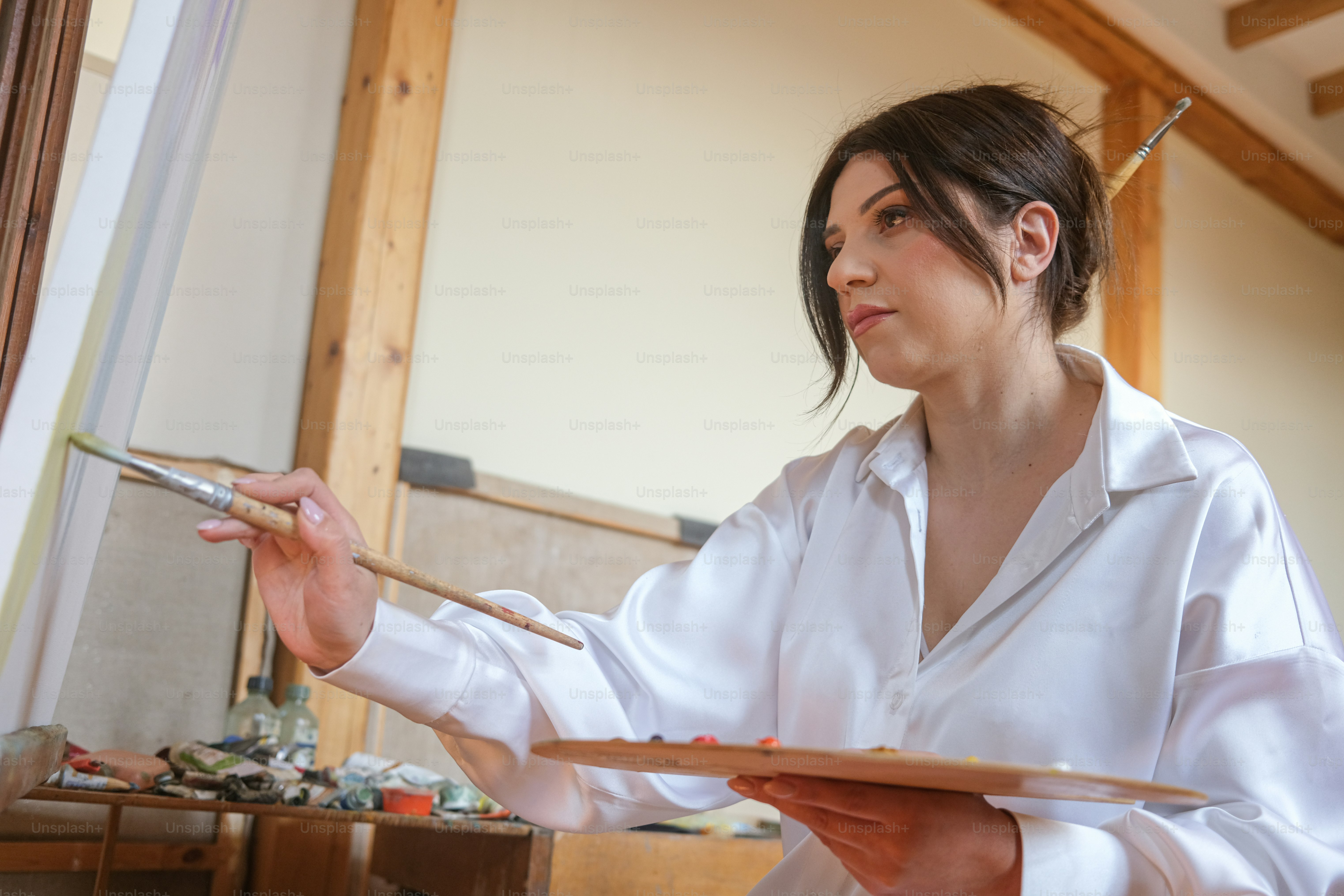 uma mulher em uma camisa branca segurando um pincel e paleta