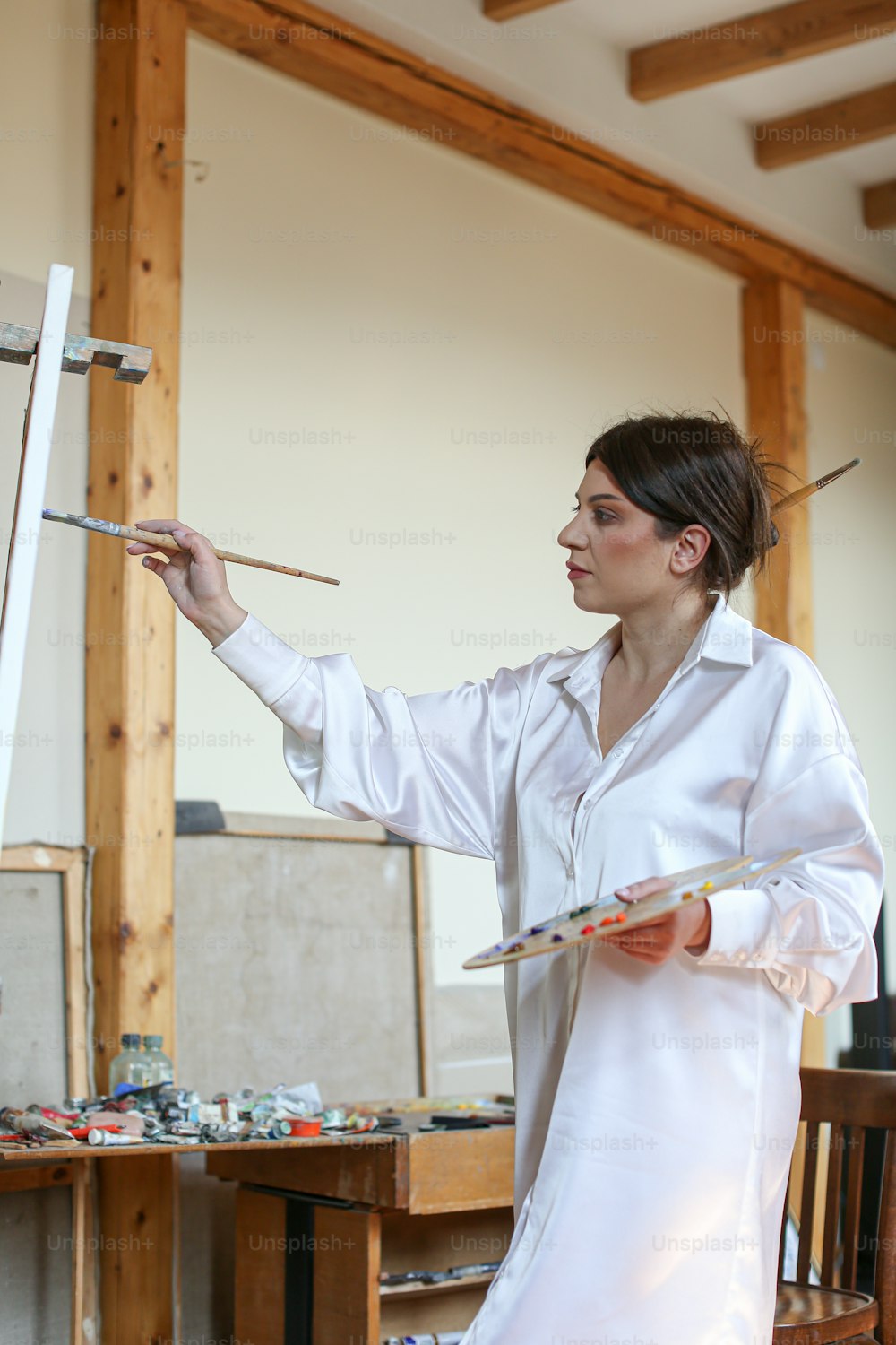 a woman in a white shirt is holding a paintbrush