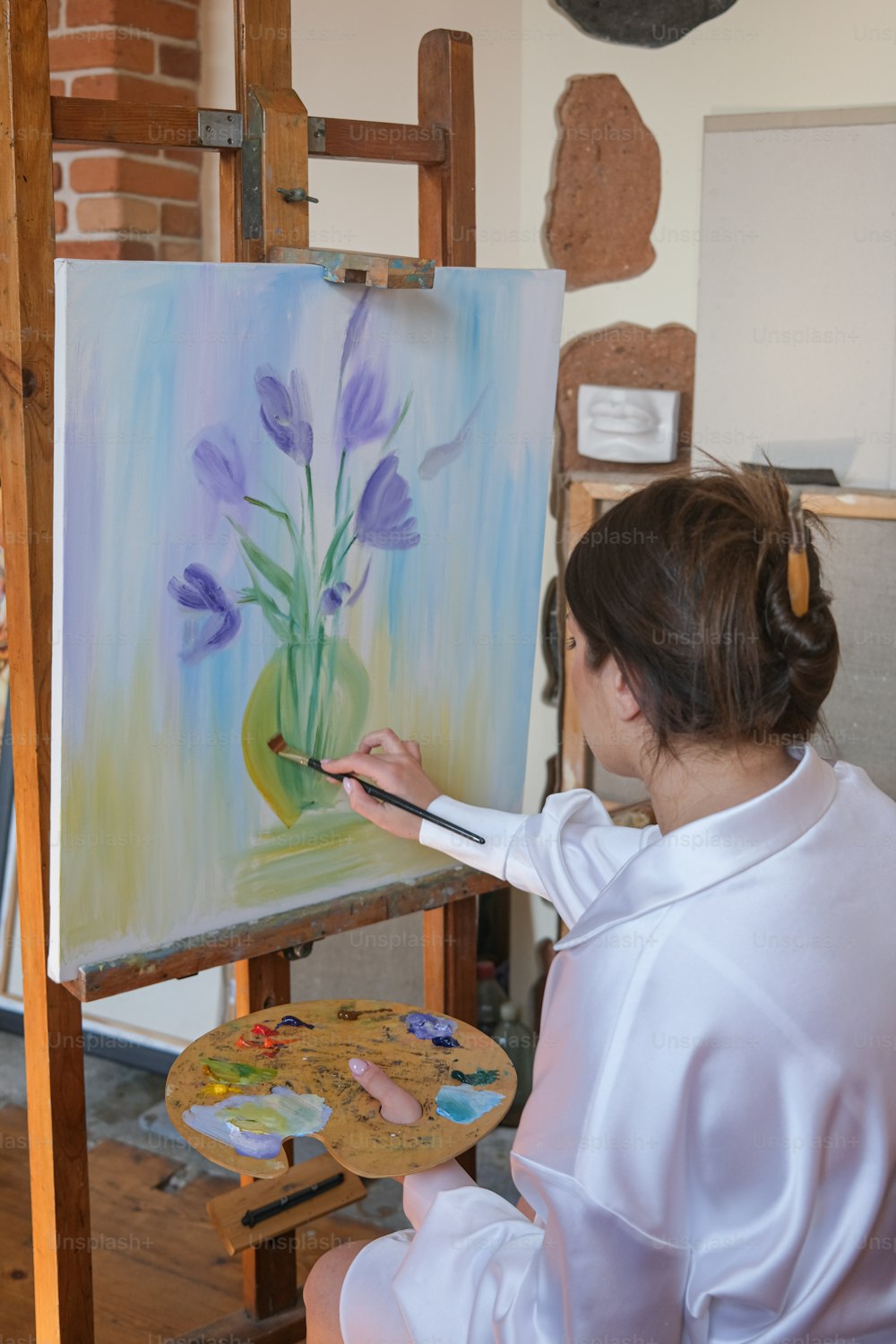 a woman is painting flowers on a canvas