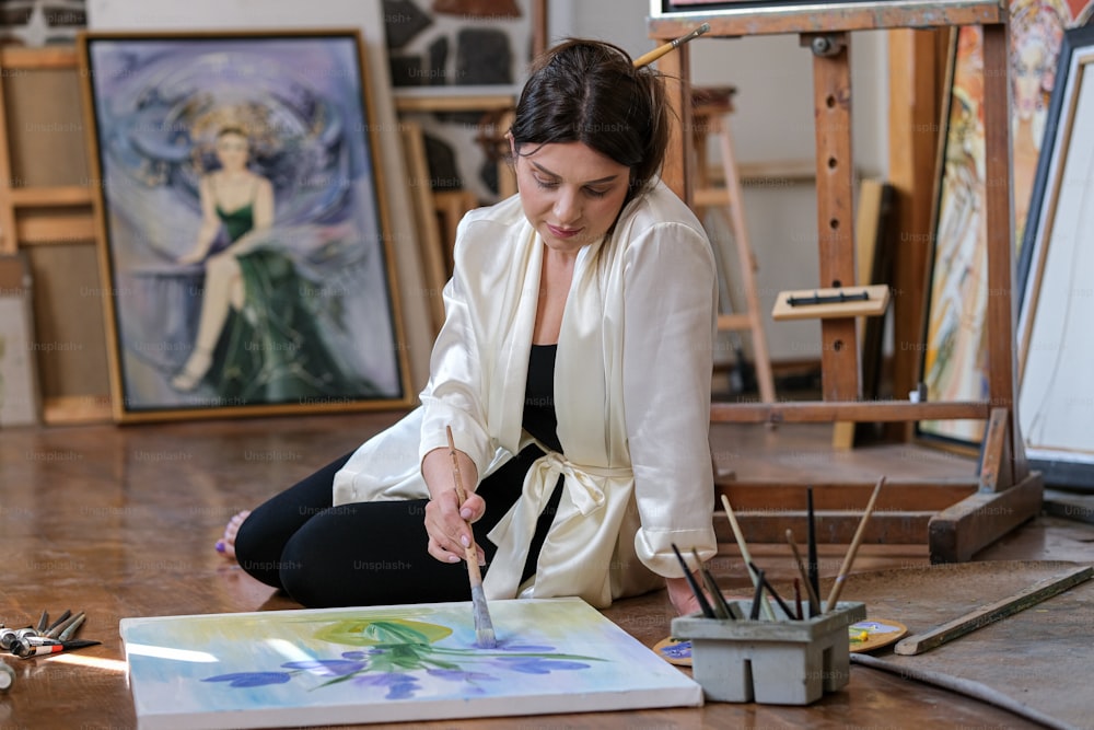 a woman sitting on the floor in front of a painting