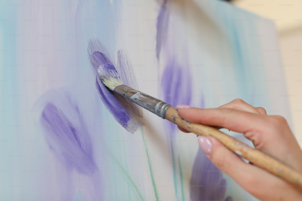 a woman is painting flowers on a canvas