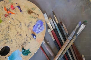 a wooden table topped with lots of paint and brushes