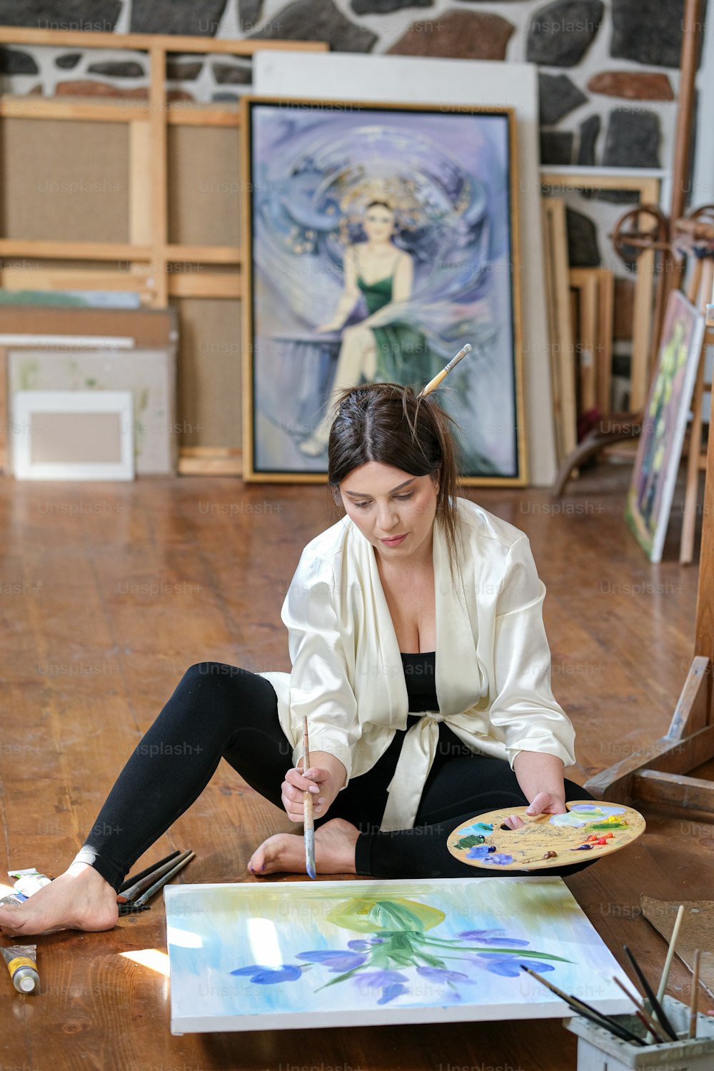 uma mulher sentada no chão pintando um quadro