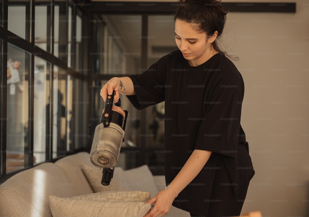 Una donna sta usando un aspirapolvere per pulire un divano
