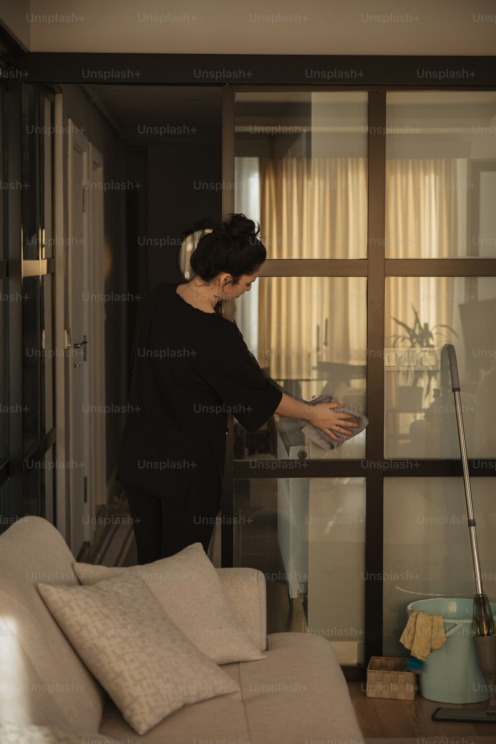 Una mujer parada en una sala de estar junto a una ventana
