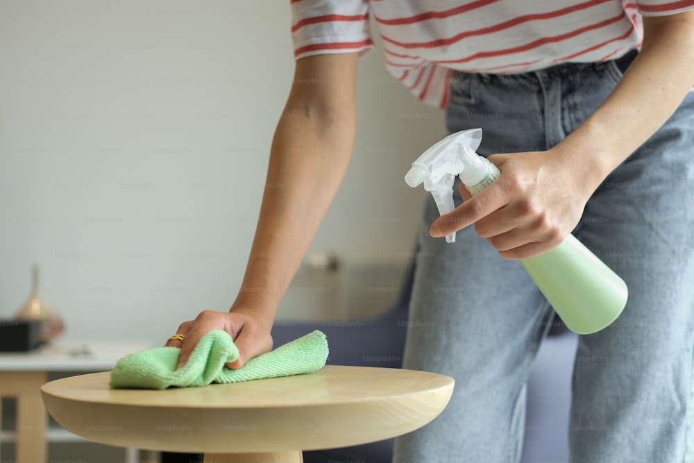 a woman is cleaning a table with a green cloth
